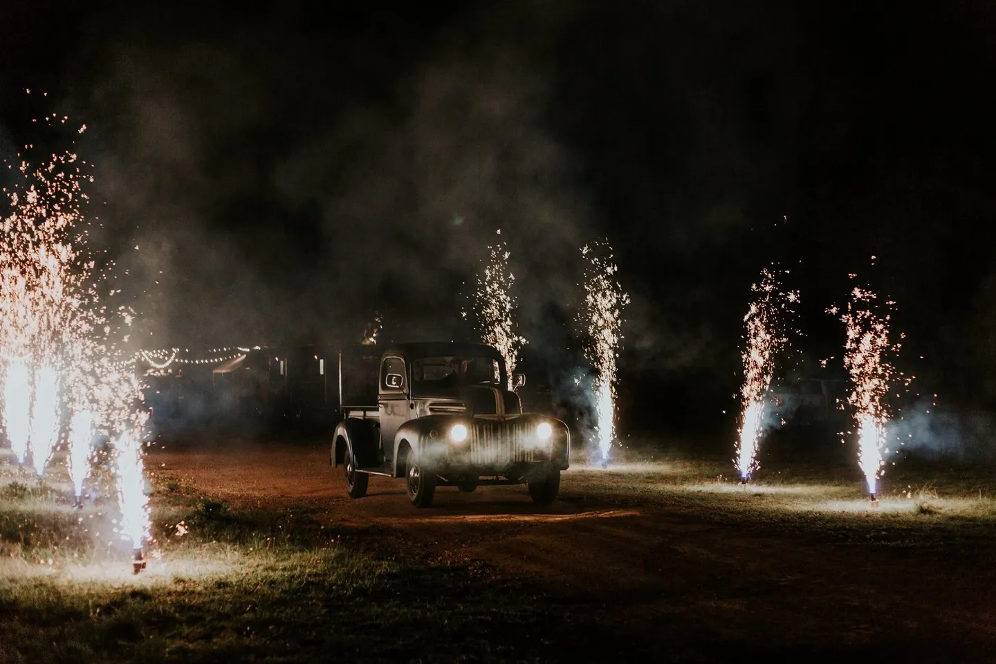 A car driving down the road with fireworks in the background.