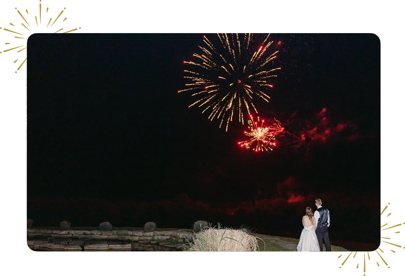 A couple standing in front of fireworks at night.