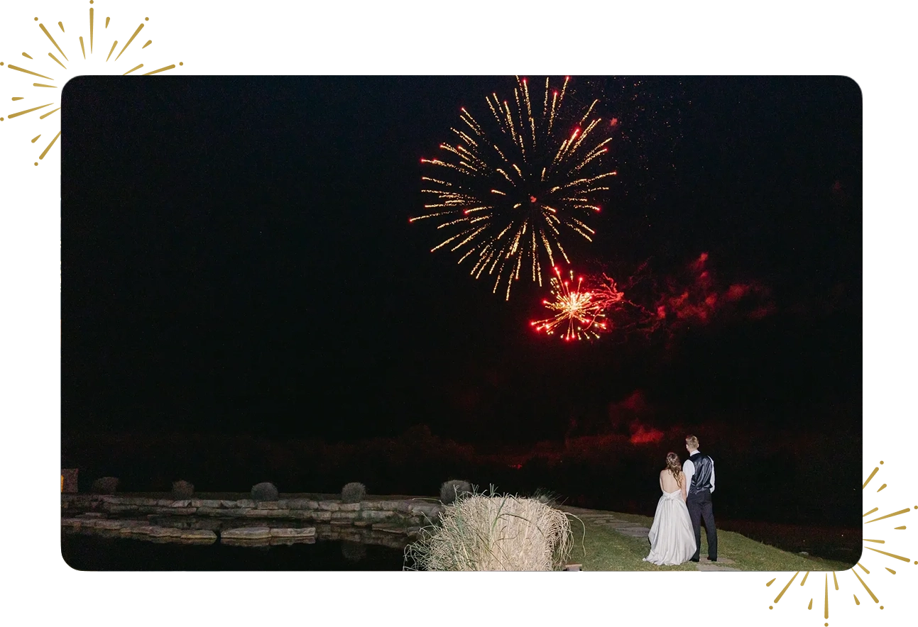 A couple standing in front of fireworks at night.